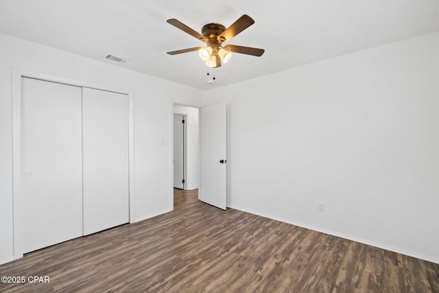 unfurnished bedroom with dark wood-type flooring, ceiling fan, and a closet