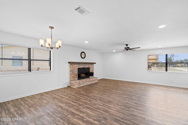 unfurnished living room with a brick fireplace, dark hardwood / wood-style flooring, and ceiling fan with notable chandelier