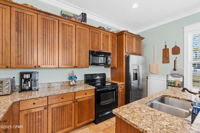 kitchen with ornamental molding, black appliances, light stone countertops, brown cabinetry, and a sink