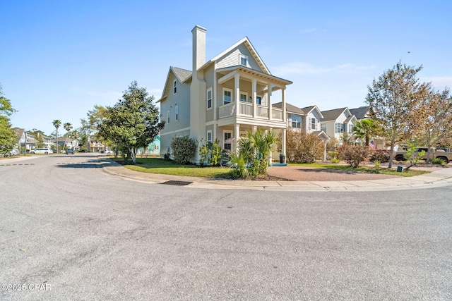 view of front of property featuring a chimney, a residential view, and a balcony