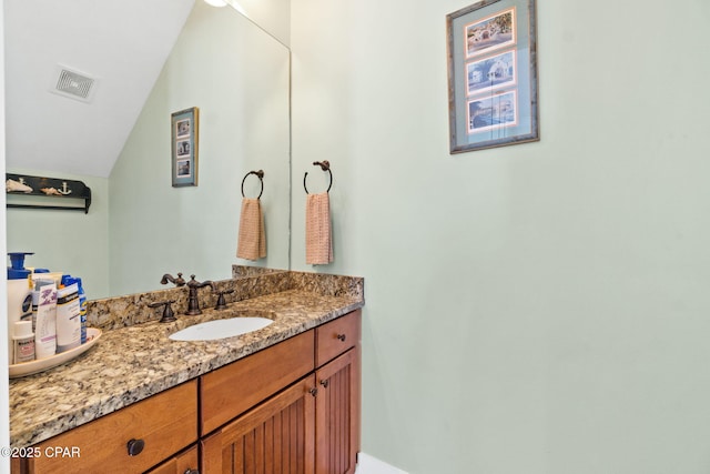 bathroom with vanity, visible vents, and lofted ceiling