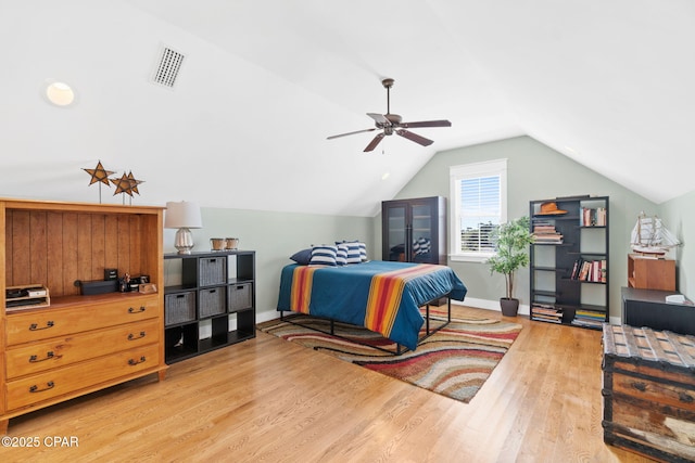 bedroom featuring a ceiling fan, visible vents, wood finished floors, lofted ceiling, and baseboards