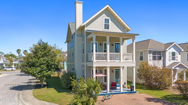 view of front of house featuring a porch, a balcony, and a chimney