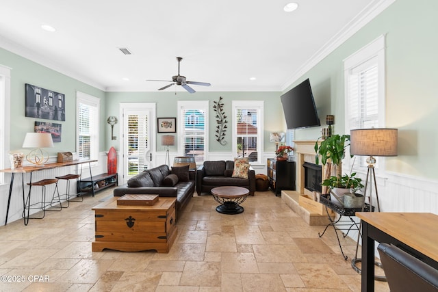 living room with stone tile floors, a ceiling fan, and ornamental molding