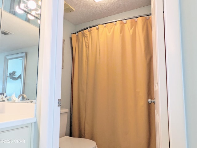 bathroom featuring visible vents, toilet, a textured ceiling, and vanity