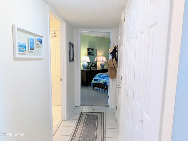 corridor featuring a textured ceiling and light tile patterned floors