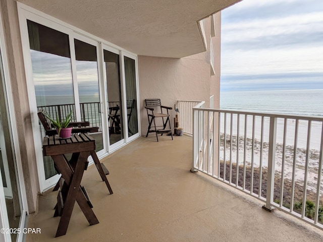 balcony featuring a view of the beach and a water view