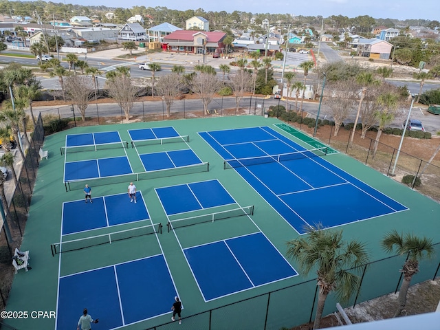 view of tennis court with fence and a residential view