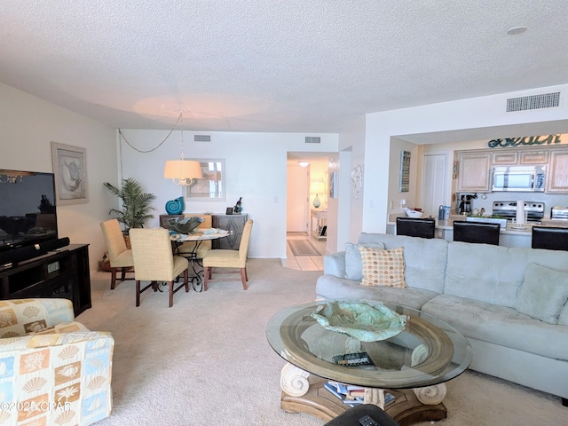 living room featuring light colored carpet, visible vents, and a textured ceiling