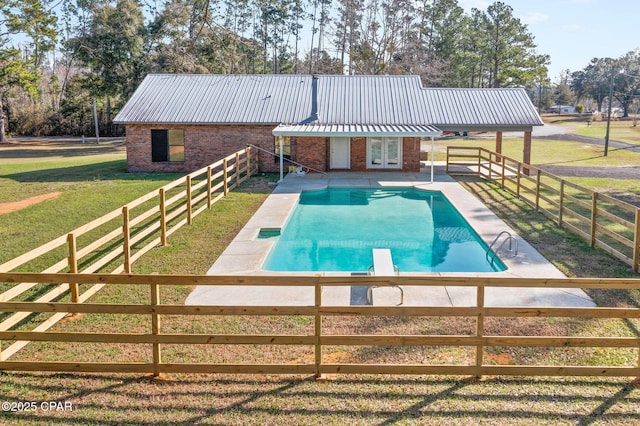 view of swimming pool with french doors, a patio, a diving board, and a lawn