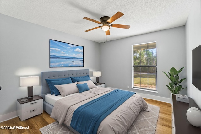 bedroom featuring ceiling fan, a textured ceiling, and light hardwood / wood-style floors