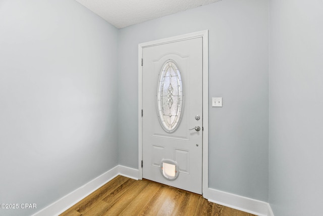 foyer entrance with light hardwood / wood-style floors and a textured ceiling