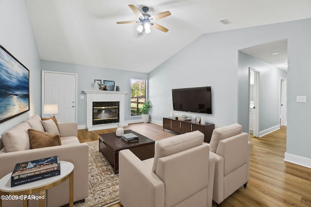 living room featuring wood-type flooring, lofted ceiling, a fireplace, and ceiling fan