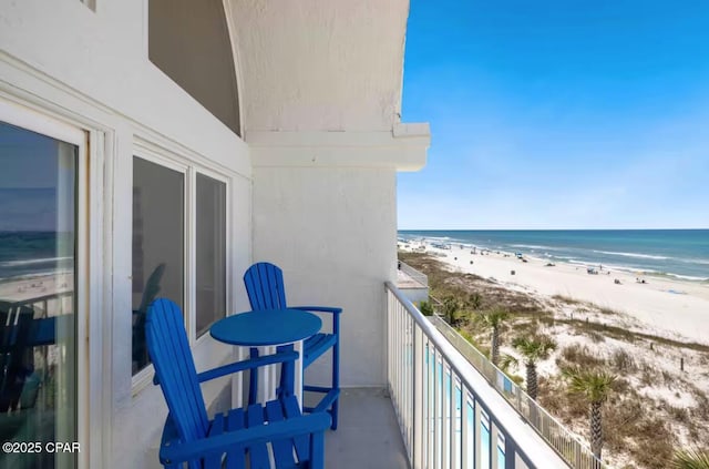 balcony with a water view and a view of the beach