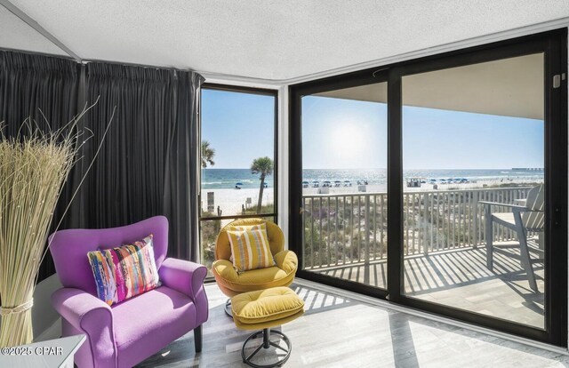 11757 Front Beach Rd Unit L104, Panama City Beach, FL 32407 - interior space featuring a view of the beach, a textured ceiling, a wall of windows, a water view, and wood finished floors