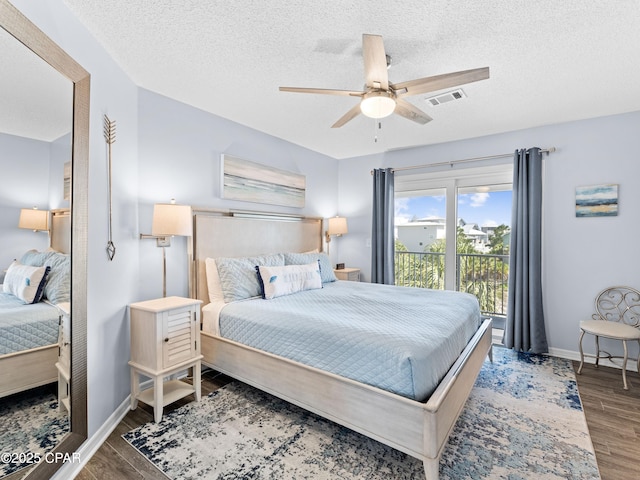 bedroom with baseboards, a textured ceiling, visible vents, and wood finished floors