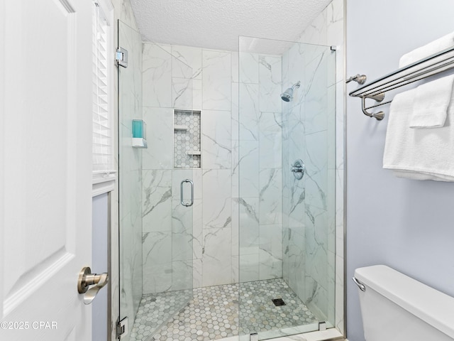 bathroom featuring a stall shower, a textured ceiling, and toilet