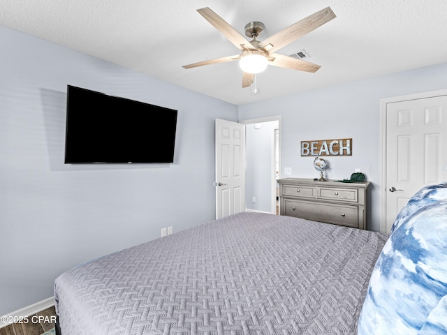 bedroom with a ceiling fan, visible vents, and a textured ceiling