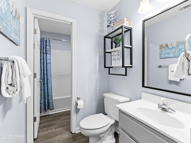 bathroom featuring visible vents, toilet, a shower with shower curtain, vanity, and wood finished floors