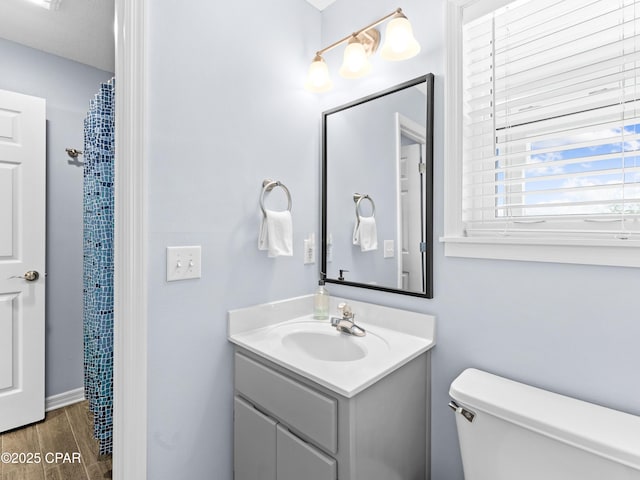 full bath featuring toilet, vanity, wood finished floors, a shower with curtain, and baseboards