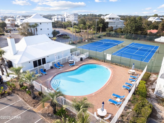 pool featuring a tennis court, a patio area, and fence