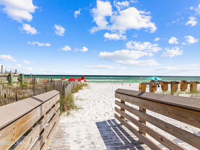 property view of water with fence and a beach view