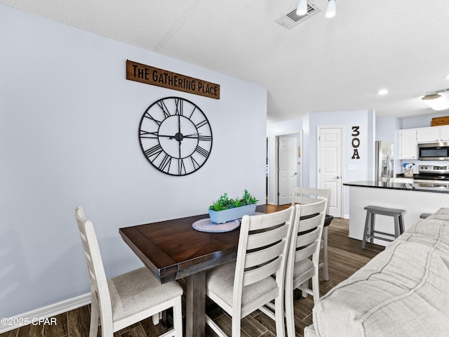 dining room with baseboards, visible vents, dark wood finished floors, and a textured ceiling