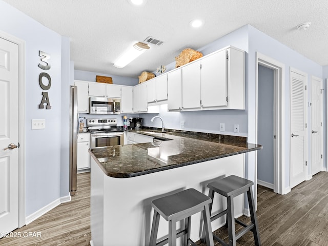 kitchen featuring white cabinetry, visible vents, appliances with stainless steel finishes, and wood finished floors