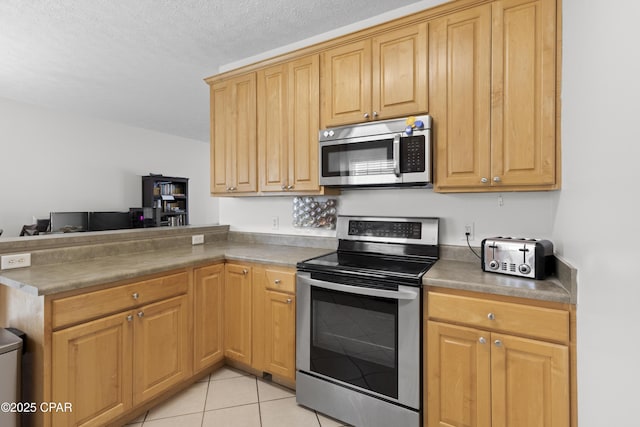 kitchen featuring a textured ceiling, appliances with stainless steel finishes, and light tile patterned floors