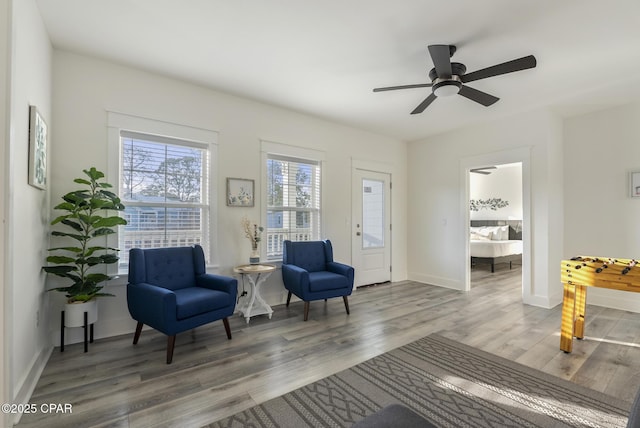 sitting room with ceiling fan and wood-type flooring