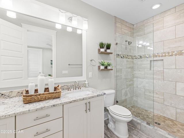 full bathroom with vanity, recessed lighting, toilet, and tiled shower