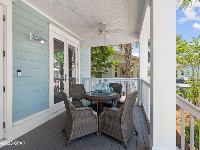 wooden deck with a ceiling fan, outdoor dining space, and covered porch