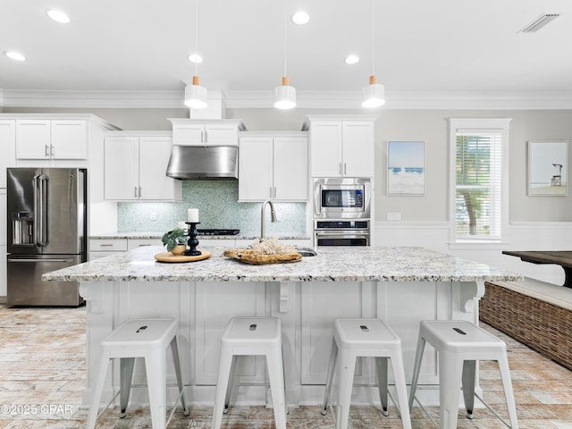 kitchen with under cabinet range hood, white cabinets, appliances with stainless steel finishes, and ornamental molding