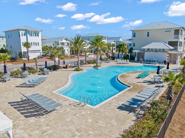 community pool with a patio area, fence, and a residential view