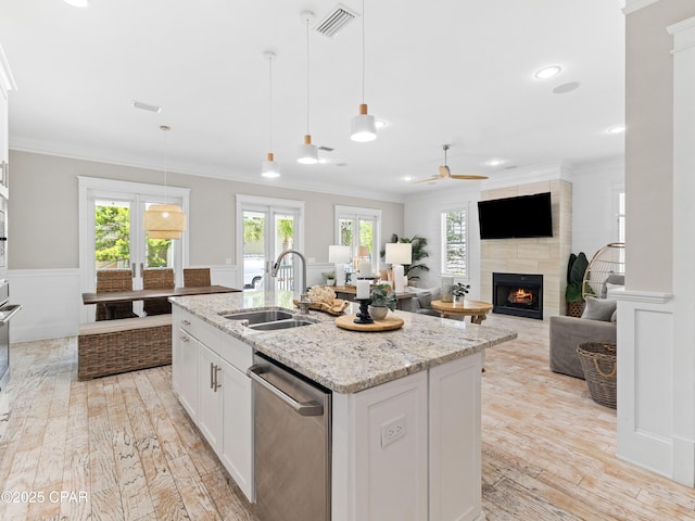 kitchen featuring ceiling fan, visible vents, a tile fireplace, dishwasher, and a sink