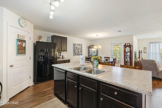 kitchen featuring a kitchen island with sink, sink, dark wood-type flooring, and black appliances