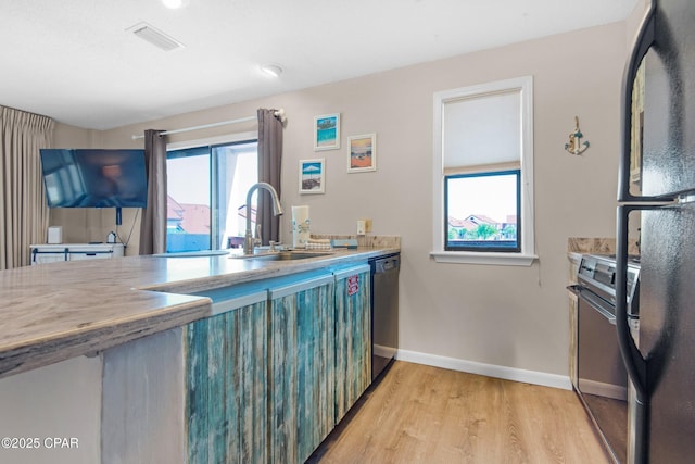 kitchen with visible vents, light wood-style flooring, freestanding refrigerator, a sink, and stainless steel dishwasher