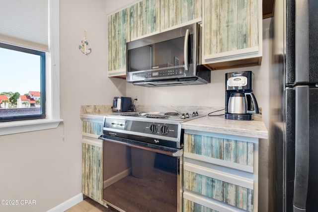 kitchen with range with electric cooktop, stainless steel microwave, freestanding refrigerator, and baseboards