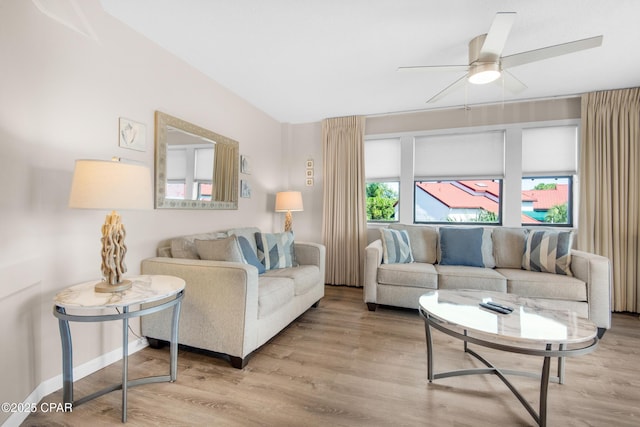 living room with ceiling fan, plenty of natural light, wood finished floors, and baseboards