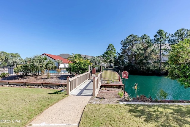 exterior space with a gate, a water view, a lawn, and fence