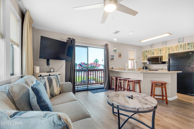 living room featuring visible vents, ceiling fan, and light wood finished floors