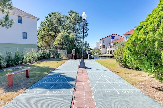 view of home's community with fence, shuffleboard, and a yard