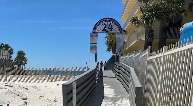 view of property exterior featuring fence and a beach view