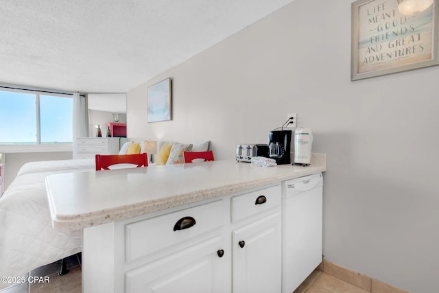 kitchen featuring light tile patterned floors, white cabinetry, white dishwasher, a textured ceiling, and kitchen peninsula