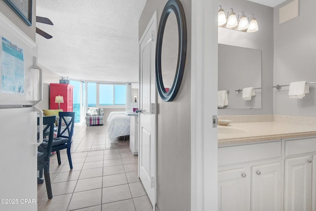 bathroom with tile patterned floors, a textured ceiling, vanity, expansive windows, and ceiling fan