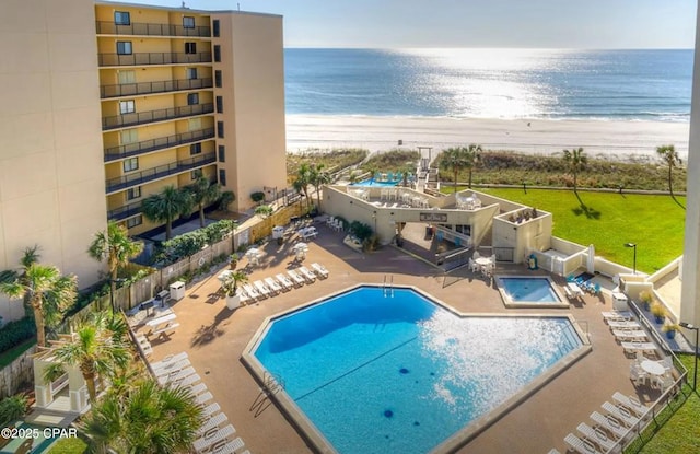 view of pool with a water view, a view of the beach, and a patio