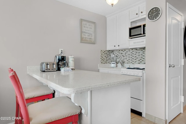 kitchen featuring a kitchen bar, white cabinetry, kitchen peninsula, decorative backsplash, and white range with electric stovetop