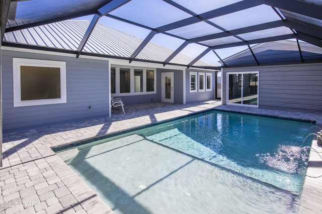 view of swimming pool with pool water feature, glass enclosure, and a patio area