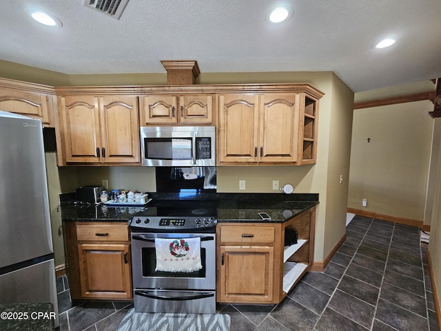 kitchen featuring stainless steel appliances, dark stone counters, and a textured ceiling