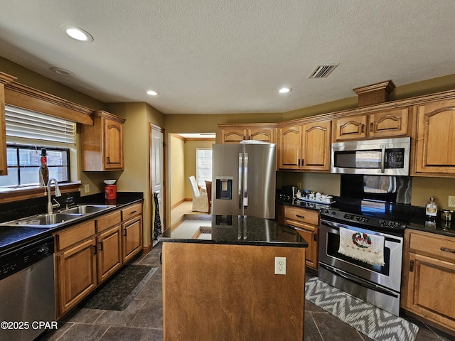 kitchen with sink, stainless steel appliances, a healthy amount of sunlight, and a center island